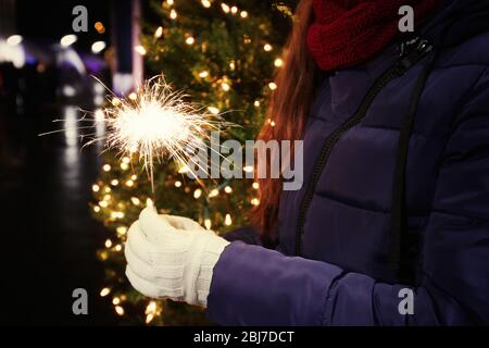 Hand der Frau, die Bengalisches Licht auf Weihnachtsgrund hält Stockfoto