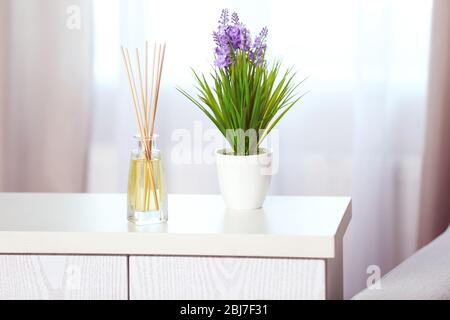Handgefertigter Reed-Freshener mit Blume auf weißer Kommode im Wohnzimmer, Nahaufnahme Stockfoto