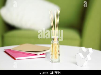 Handgefertigter Reed-Freshener mit Notizbüchern auf weißem Tisch im Wohnzimmer, aus nächster Nähe Stockfoto