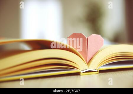 Buch und herzförmiges Lesezeichen auf einem Holztisch Stockfoto