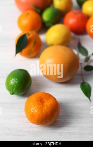 Frische Zitrusfrüchte mit grünen Blättern auf Holzhintergrund Stockfoto