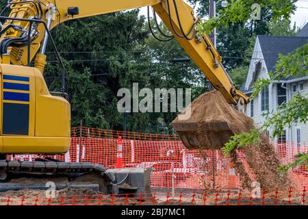 Frontlader gräbt auf einer neuen Baustelle in einem belebten Stadtgebiet Stockfoto