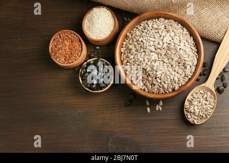 Geschälte Sonnenblumen, Flachs und Sesam auf Holztischuntergrund, Nahaufnahme Stockfoto