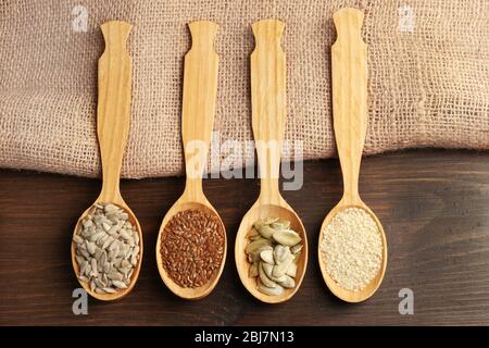 Sesam, Flachs, Kürbis und Sonnenblumenkerne in Holzlöffeln auf dem Tisch, Nahaufnahme Stockfoto