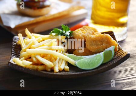 Pommes Frites und Snacks mit einem Glas Becher helles Bier auf einem dunklen Holztisch, ganz nah Stockfoto