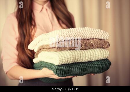 Stapel von Stricksachen in weiblichen Händen Nahaufnahme Stockfoto