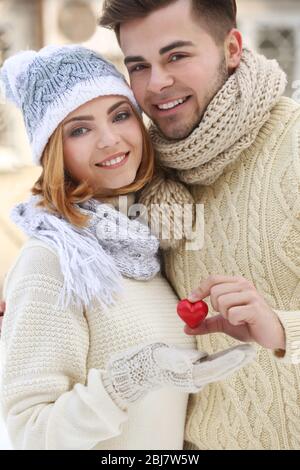 Junges Paar in der Liebe hält kleine rote Herz im Winter draußen Stockfoto