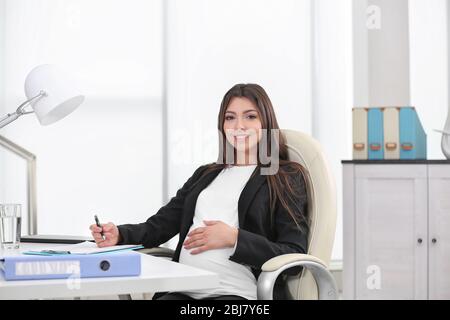 Schwangere Frau sitzt an ihrem Arbeitsplatz im Büro Stockfoto