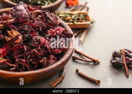 Vielfalt von Tee in Holzschalen und Schaufel auf grauem Hintergrund, Nahaufnahme Stockfoto