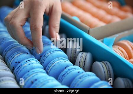 Weibliche Hand, die schmackhafte Macaroon aus der Box Stockfoto