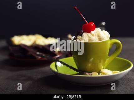 Schokoladenkuchen in einem grünen Becher mit Schlagsahne und einer Kirsche auf der Oberseite, Nahaufnahme Stockfoto