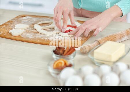 Junge Frau, die die Herzen in einem Teig auf der Küchentheke ausschneidet Stockfoto