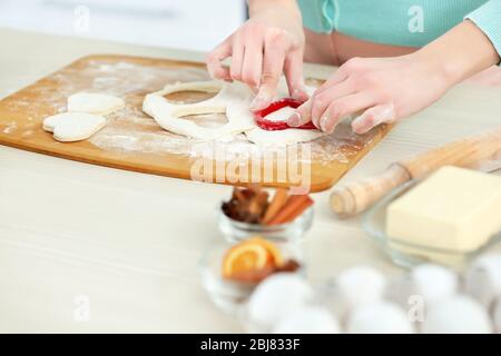 Junge Frau, die die Herzen in einem Teig auf der Küchentheke ausschneidet Stockfoto