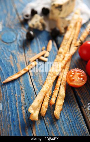 Brot klebt auf einem blauen Tisch, grissini mit Käse und Tomaten, aus nächster Nähe Stockfoto