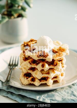 Ricotta Käse schabt für Keto Ernährung. Stapel von Ricotta und Zitrone belgischen Waffeln mit Eislöffel dekoriert. Platz für Text oder Design kopieren. Natürliches Tageslicht bei Sonnenuntergang. Vertikal. Stockfoto