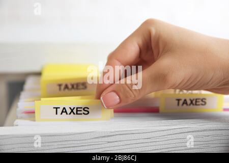 Handsuche durch verschiedene Steuerdokumente in offener Schublade Stockfoto