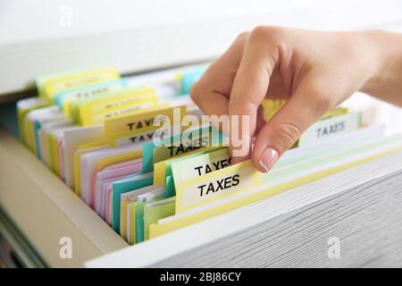 Handsuche durch verschiedene Steuerdokumente in offener Schublade Stockfoto