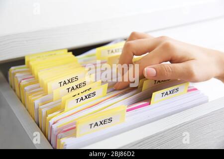 Handsuche durch verschiedene Steuerdokumente in offener Schublade Stockfoto