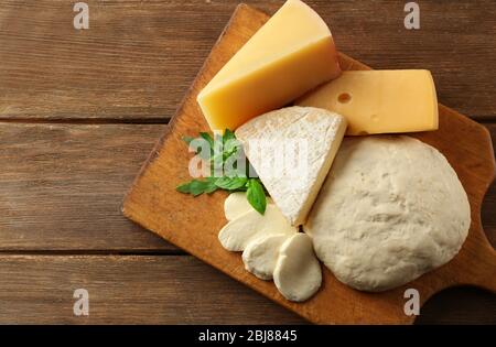 Frischer italienischer Pizzateig mit verschiedenen Käsesorten auf Holzhintergrund Stockfoto