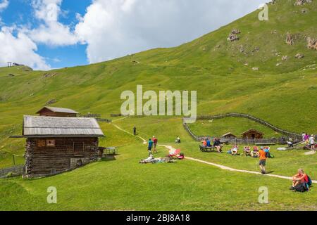 Wanderer ruhen sich auf einer Wiese bei einer Berghütte in Seceda im Val Garden, Italien Stockfoto