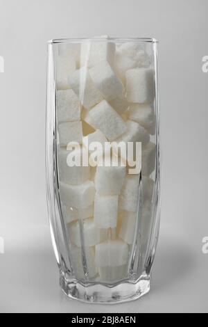 Highball Glas mit Klumpenzucker auf grauem Hintergrund gefüllt Stockfoto