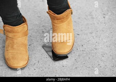 Weibliche Stiefel zerquetschen ein Handy auf dem Bürgersteig Stockfoto