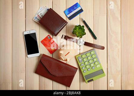 Sparschwein mit Handy, Geldbörse und anderem Zubehör auf Holztisch, Draufsicht Stockfoto