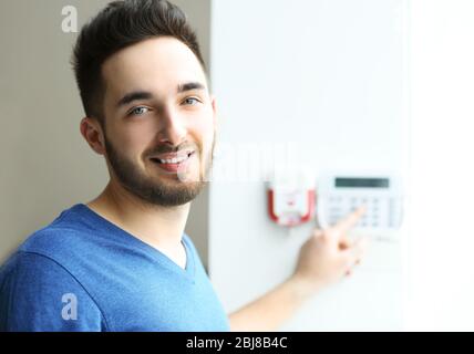 Mann, der den Code auf der Tastatur des Sicherheitssystems im Innenbereich eingibt Stockfoto