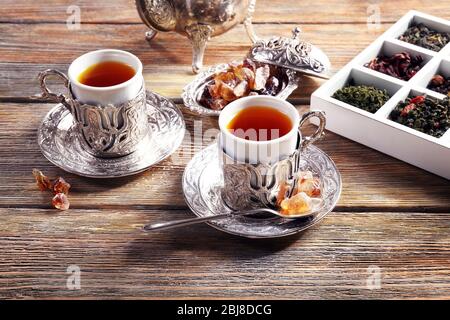 Schwarzer Tee in Tassen mit silbernem Glashalter auf Holztisch Stockfoto