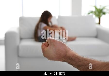 Die Faust des Vaters als Strafe und seine junge Tochter auf der Couch Stockfoto