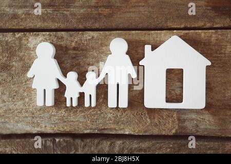 Familienfigur mit einem Haus auf Holzhintergrund Stockfoto