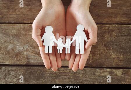 Weibliche Hände halten Familienfigur auf Holzhintergrund Stockfoto