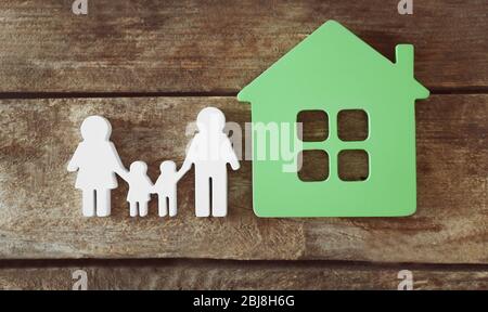 Familienfigur mit einem Haus auf Holzhintergrund Stockfoto