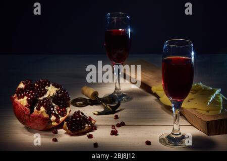 Gläser frischer Granatapfelwein, reifer Granatapfel. Käse auf dem Brett. Copyspace. Stockfoto