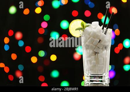 Highball Glas mit Klumpenzucker auf dunklem Bokeh Hintergrund Stockfoto