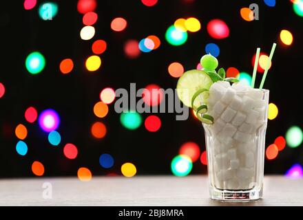 Highball Glas mit Klumpenzucker auf dunklem Bokeh Hintergrund Stockfoto