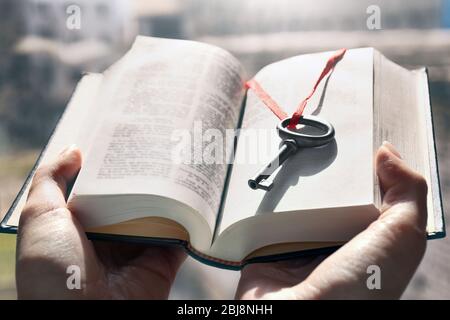 Hände, die ein Buch mit Vintage-Schlüssel darin halten. Nahaufnahme Stockfoto