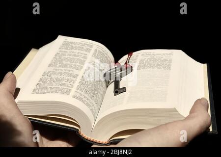 Hände mit einem Buch mit Vintage-Schlüssel auf schwarzem Hintergrund. Stockfoto