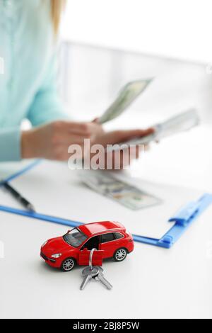 Kauf Auto Konzept. Rotes Spielzeugauto mit Schlüsseln auf dem Tisch Stockfoto