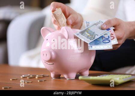 Junger Mann mit Sparschwein auf Holztisch. Stockfoto