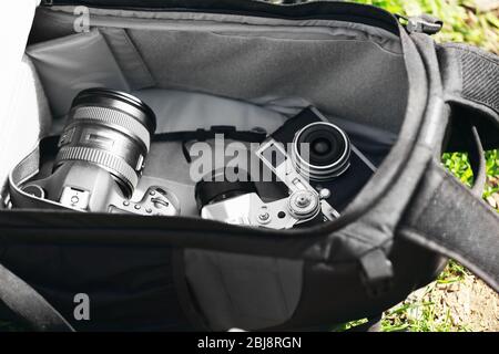 Moderne und alte Kameras im offenen Rucksack im Freien Stockfoto