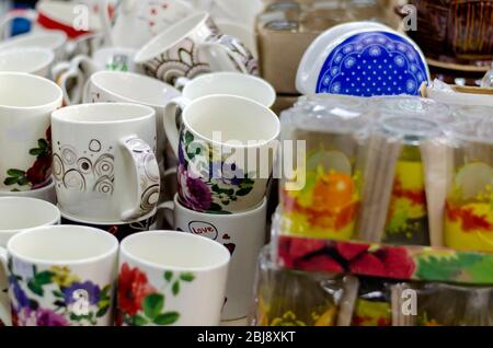 Mehrfarbige Keramikbecher in einem Schaufenster. Ein Haufen von bunten Tassen, Souvenirs und andere Küchenutensilien. Nahaufnahme. Selektiver Fokus. Stockfoto