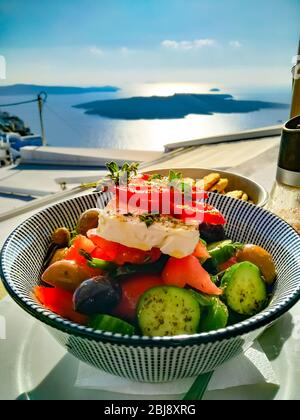 Sehr leckerer griechischer Salat mit einem fantastischen Blick auf den Vulkan Santorini, Griechenland Stockfoto