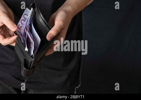 Ein Mann mit einer schwarzen Brieftasche voller europäischer Währung oder europäisches Geld. In einer schwarzen Geldbörse Banknote für 500 Euro. Erhöhung der Gehälter und Renten, werden Stockfoto