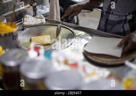 Hände von Straßenverkäufer Kochen Thai Stil süße Roti Brot auf Stahl Roti Pfanne oder große flache Pfanne. Genießen Sie Thailand Street Food. Stockfoto