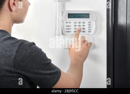 Mann, der den Code auf einem Hausalarm drückt Stockfoto