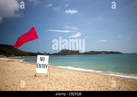 Konzept geschlossener Strand, privater Strand, funktioniert nicht. Es gibt eine rote Flagge und ein Schild, das besagt, dass an einem leeren tropischen Strand an einem schönen Tag kein Zutritt ist. Stockfoto