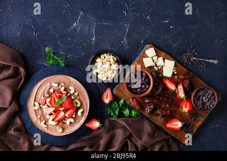 Vegane Cashew-Torte mit weißer und dunkler Schokoladenfüllung und No-Bake Datteln, Kakao- und Pekannüsse, darauf mit frischen Erdbeeren verziert Stockfoto