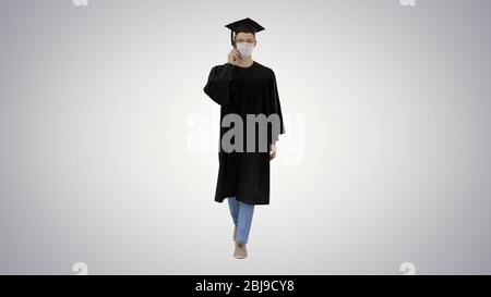 Junge Absolvent Student einen Anruf mit Smartphone mit medizinischer Maske auf Gradient Hintergrund. Stockfoto