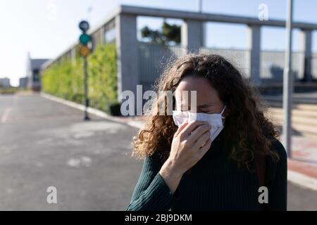 Kaukasische Frau mit einer Schutzmaske und hustet auf den Straßen Stockfoto